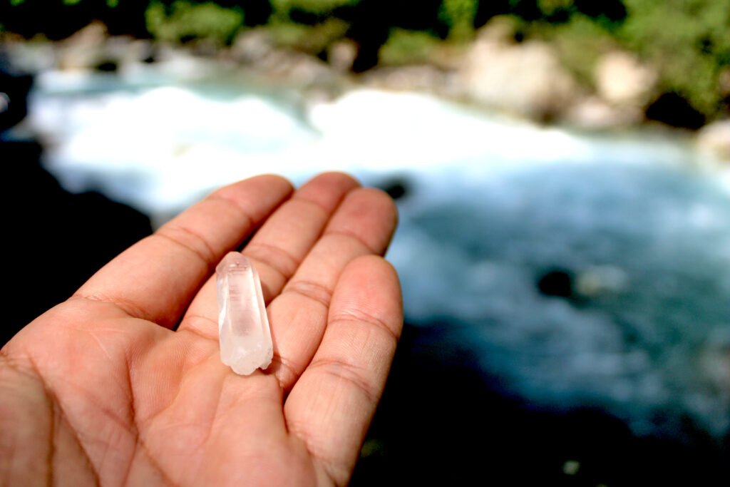 Cristal de roche naturel utilisé en lithothérapie, présenté en gros plan dans une main, idéal pour purification et rituels énergétiques.
