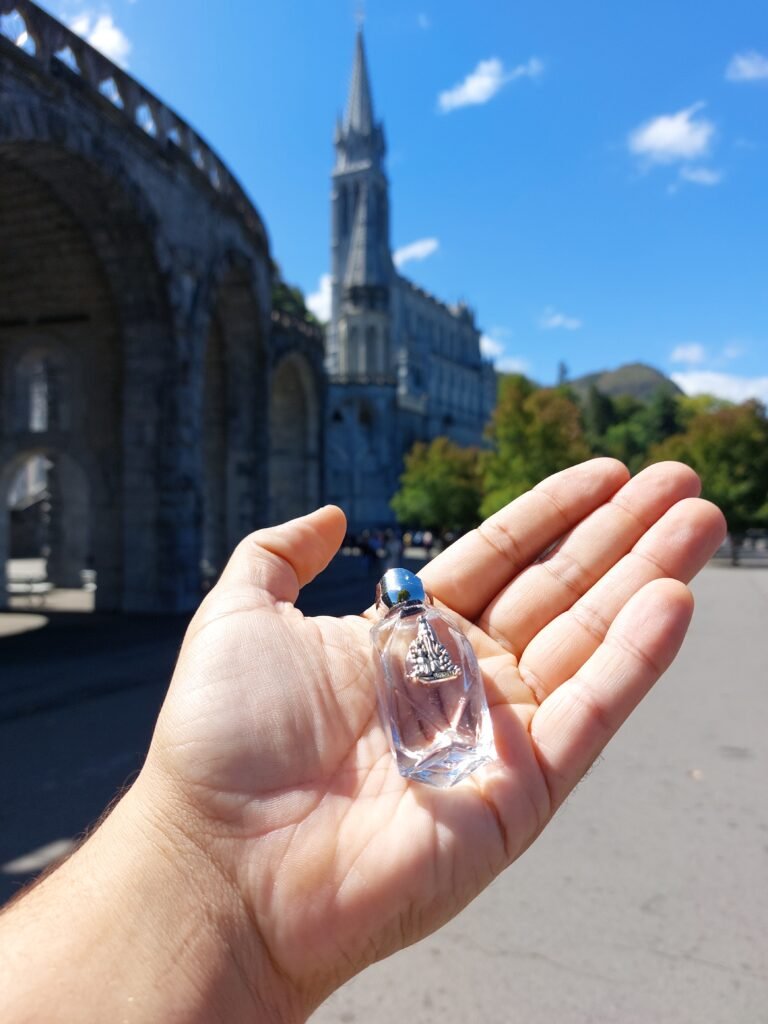 Fiole d'eau de Lourdes devant le sanctuaire